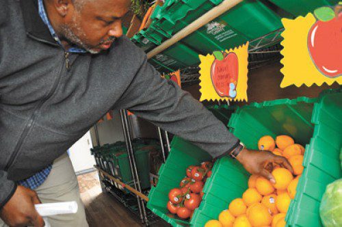 An Indianapolis resident chooses fruit from the “Garden on the Go” mobile produce truck, which recently made its debut. Reports show that 68 percent of residents of low-income neighborhoods live in areas without adequate access to healthy foods. The truck will make monthly stops to such areas in Marion County. 