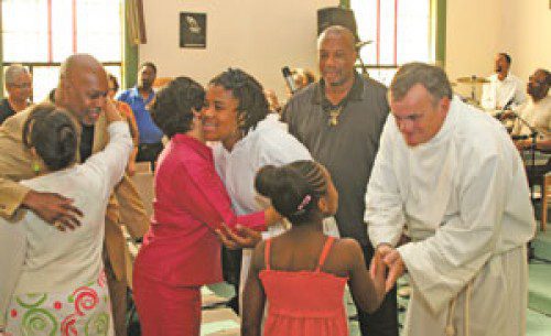 

<p>Reggie Ash (background) looks on while his daughter Adrienne Ash<br />
and deacon candidate Brad Anderson greet some of the parishioners<br />
during the “Sign of Peace” at the mass.</p>
<p>“><figcaption class=