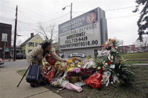 Louise Backus of Binghamton, adds to a memorial pile of flowers at the American Civic Association in Binghamton, N.Y., Tuesday, April 7, 2009. (AP Photo/Mike Groll)