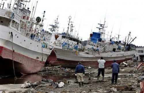 People look at fishing boats stranded by the March 11 tsunami at Kesennuma, Miyagi Prefecture, northern Japan, Wednesday, March 23, 2011.  (AP Photo/Shizuo Kambayashi)