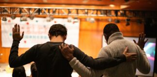 two men holding ear others hand