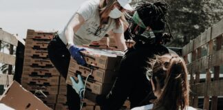 woman in white t-shirt and blue denim jeans sitting on brown cardboard box