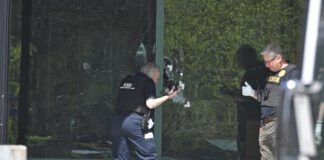 A Louisville Metro Police technician photographs bullet holes in the front glass of the Old National Bank building in Louisville, Ky., Monday, April 10, 2023. A shooting at the bank killed and wounded several people police said. The suspected shooter was also dead. (AP Photo/Timothy D. Easley)