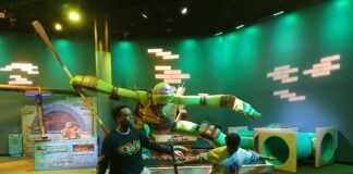 Just inside the exhibit are statues of each Teenage Mutant Ninja Turtle. Djibril, 17, and Adama, 12, visited the exhibit with Recorder Production Manager Jeana Ouattara during its opening March 9. (Photo/provided)