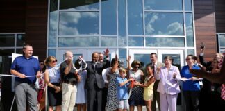 Students, teachers, and administrators cut a ribbon in front of a new elementary school