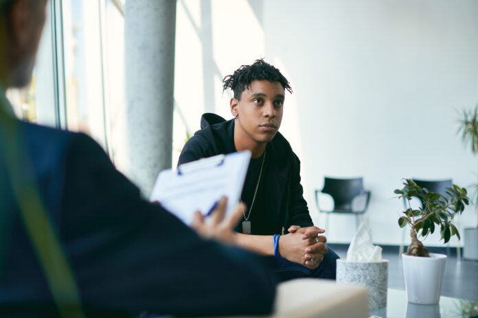 Black teenage boy having counselling with mental health professional during therapy session. (Getty Images)