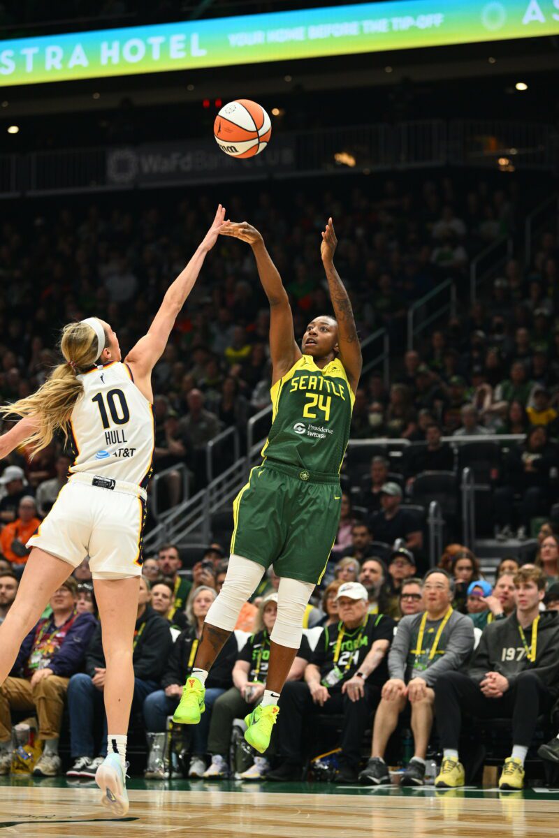 WNBA player shooting a basketball over another WNBA player.