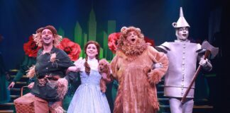 From left, the Scarecrow (Joey Boos), Dorothy (Grace Atherholt), the Cowardly Lion (Brett Mutter), and the Tin Man (Jaden Kindle) are excited to see the Emerald City in Beef & Boards Dinner Theatre’s production of The Wizard of Oz, now on stage through July 7.