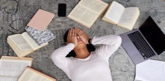 student surrounded by books, stressed out, test anxiety.