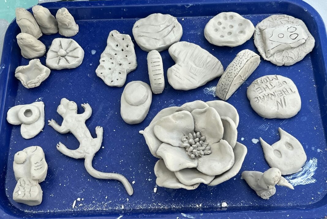 A bunch of clay ceramic objects sit on a blue tray