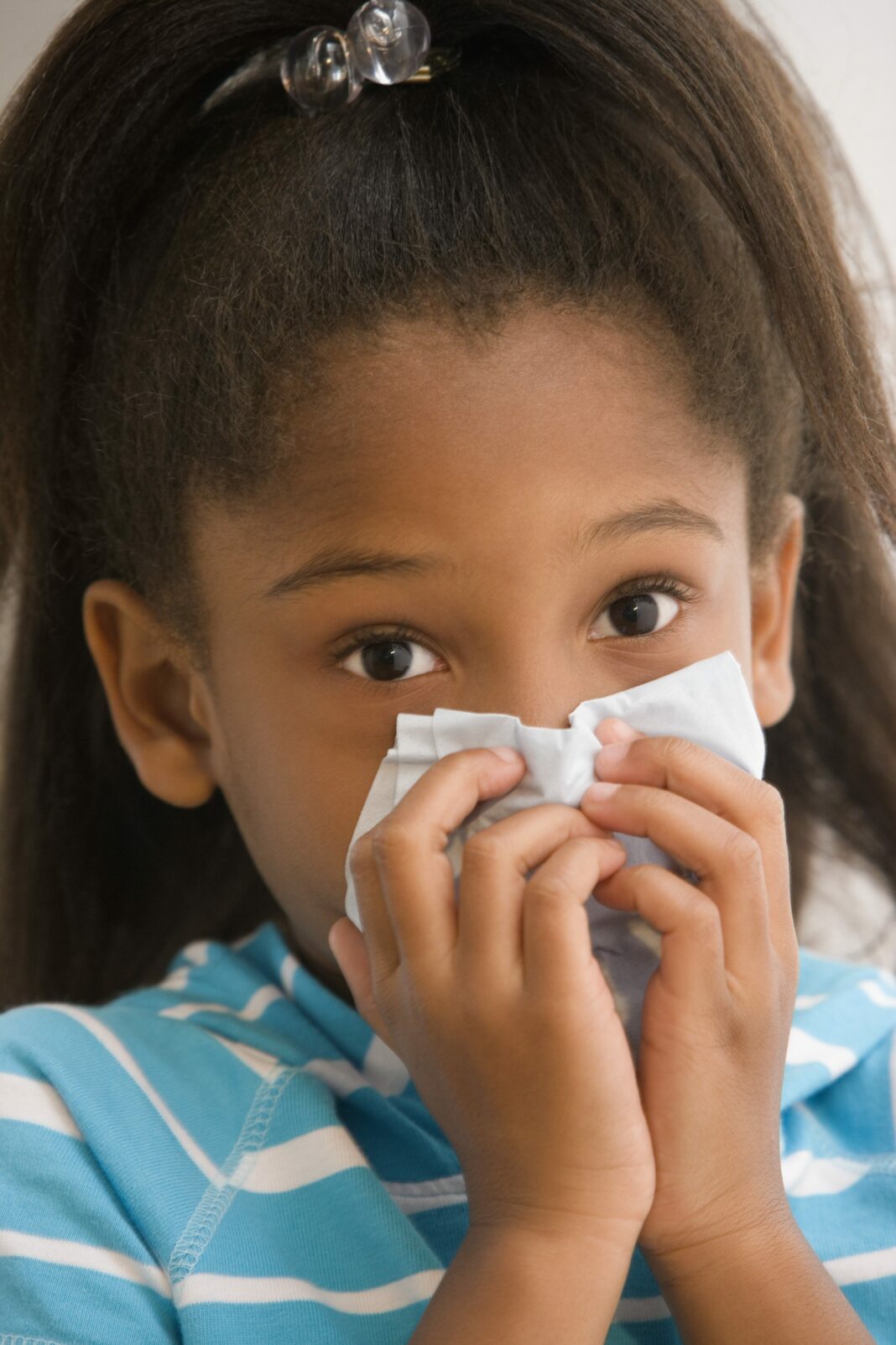 young girl blowing her nose