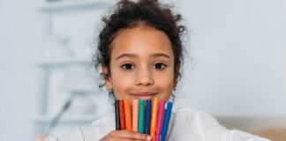 adorable african american kid holding colored felt pens and looking at camera at home
