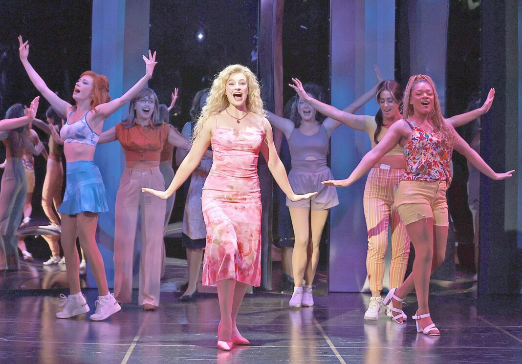 A woman in pink as dancers surround her