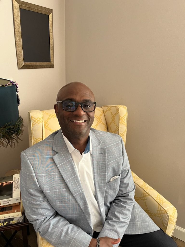 man in grey suit sits on yellow chair