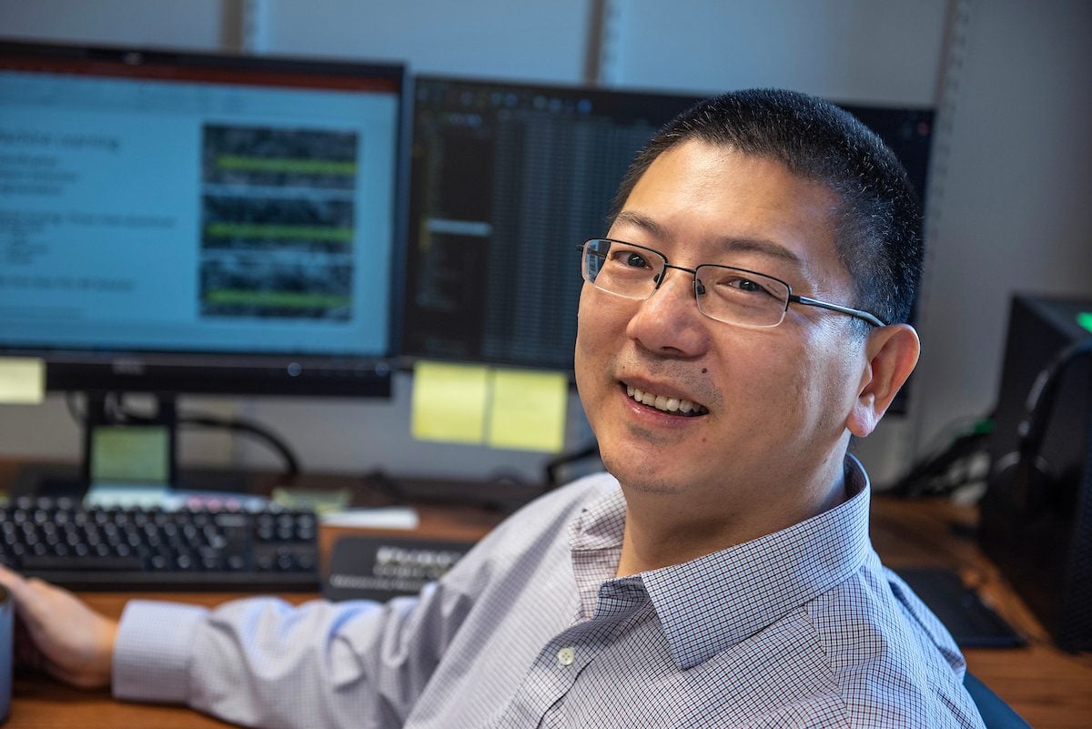 Man with glasses posed next to computer