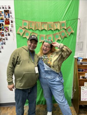woman and man stand in front of green background
