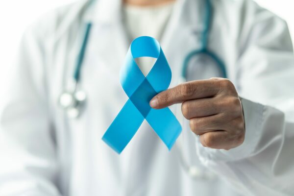 doctor in white coat holds up blue ribbon for prostate cancer awareness