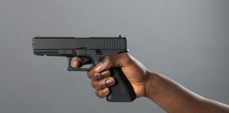 Hand of a Black man holding a handgun taking aim
