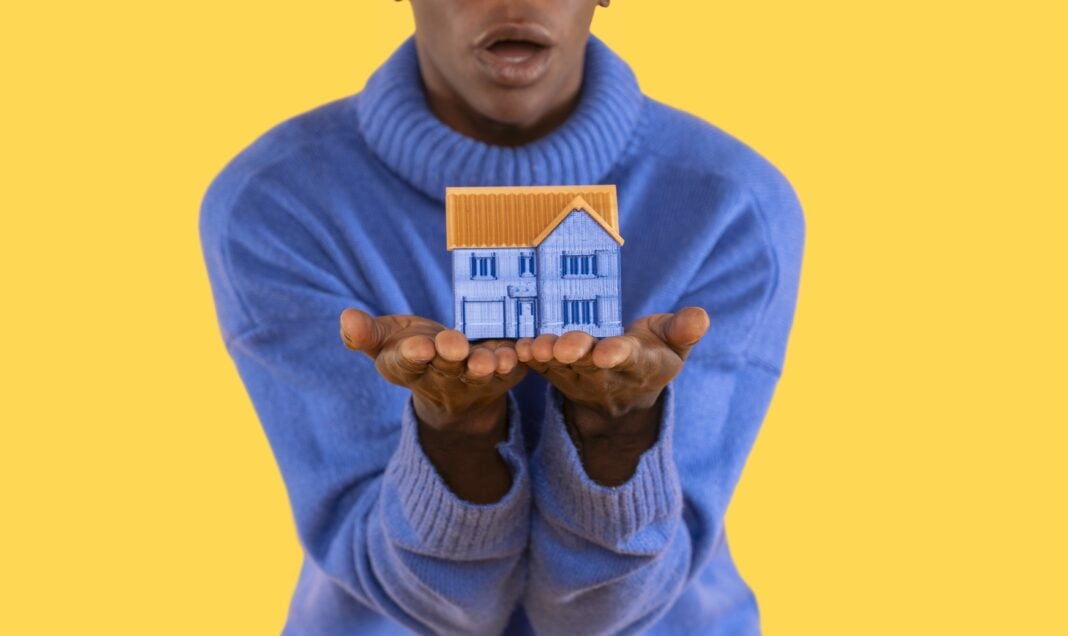 Big house in hand on blue background. trying to find an affordable house to buy or rent concept