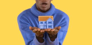 Big house in hand on blue background. trying to find an affordable house to buy or rent concept