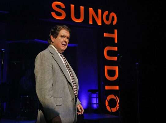 man in suit stands in front of sun studio sign