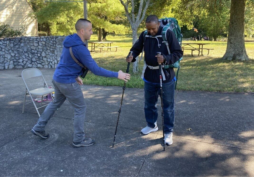 staffer helps refugee prepare for hiking