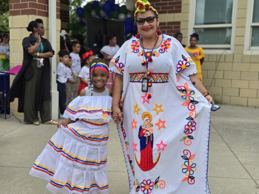 young student from Global Prep Academy stands with her teacher in cultural garb