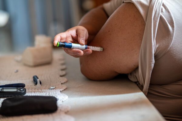 Portrait of a Latin woman at home taking an insulin shot on her own arm.