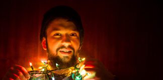 A man tangled up in christmas/holiday lights and decorations.