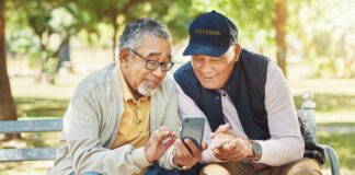 Elderly men, friends and phone in park, reading and army memory with thinking, relax and sunshine. Senior military veteran, smartphone and talk on bench, nostalgia and remember service in global war