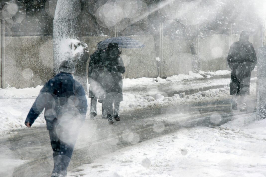 people walking on city street under snowing