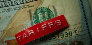 Red Tariffs label on a hundred dollar bill closeup