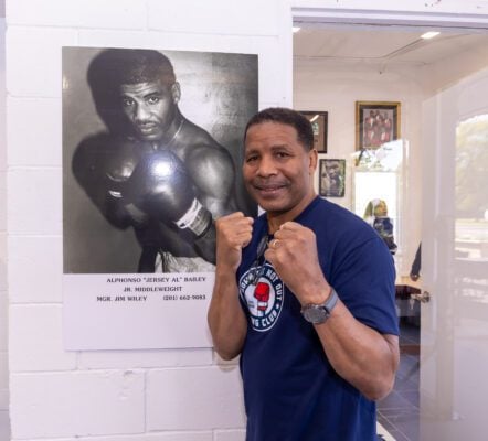 Boxer Alphonso Bailey posing in front of a photo of himself at his Down But Not Boxing gym in 2025.