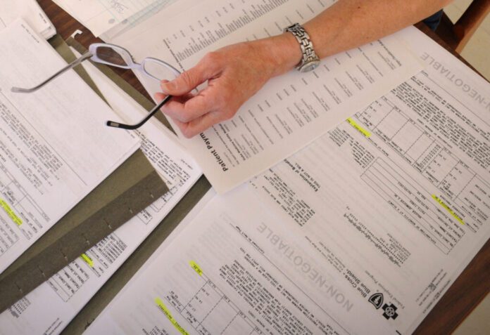 A cancer patient’s medical bills are spread on a kitchen table in a home in Salem, Va., in this 2011 file photo. A new Trump administration rule would override more than a dozen state laws that shield consumers’ credit reports from medical debt. (Photo by Don Petersen/Associated Press)