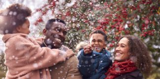 Parents Carrying Children As Family Enjoy Fall Or Winter Walk In Countryside In Snow