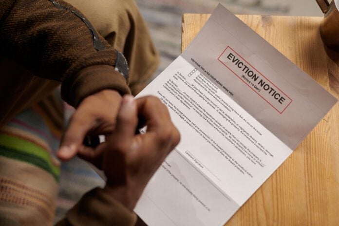 Person Reading Eviction Notice at Wooden Table eviction notice. (Photo/Getty Images)