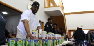 Volunteers stack canned goods at Fountain Square Church of Christ on the Southeast side of Indianapolis during a food distribution event Saturday, Nov. 8, 2025 organized by the city’s Office of Public Health and Safety. (Photo via WFYI)