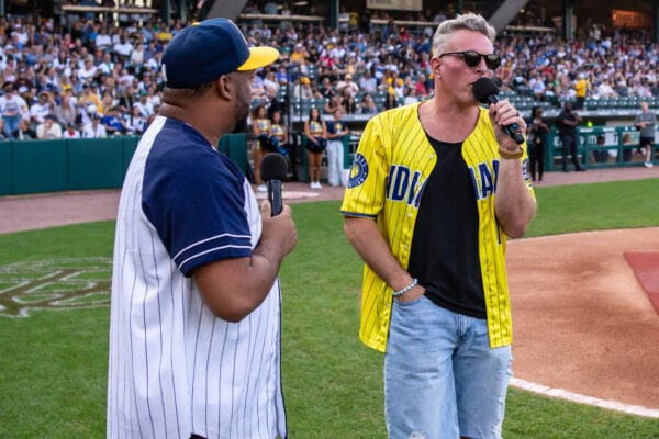 Sports analyst and former Colts punter Pat McAfee speaks into a microphone to address the crowd in downtown Indianapolis alongside the event's emcee. (Photo/Josh Herd)