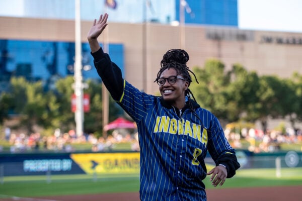 Indiana Fever guard Kelsey Mitchell smiles and waves to the crowd while taking the field in a blue pinstripe Indiana jersey at the Pacers Foundation Charity Softball Classic at Victory Field. (Photo/Josh Herd)