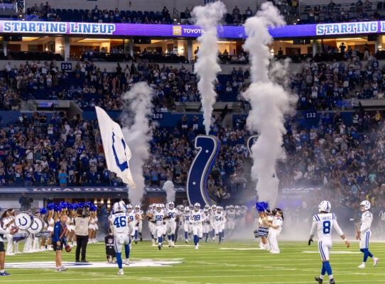 Indianapolis Colts players run out of the tunnel through smoke and pyrotechnics during pre-game player introductions, accompanied by cheerleaders and the drumline on the field on Aug. 29, 2026, at Lucas Oil Stadium, in downtown Indianapolis, Indiana. (Photo/Walt Thomas)