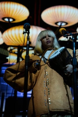 Erykah Badu stands on stage holding a djembe drum under warm, glowing stage lights on Sept. 22, 2026, at the Everwise Amphitheater at White River State Park, in Indianapolis, Indiana. (Photo/Mia Moore)
