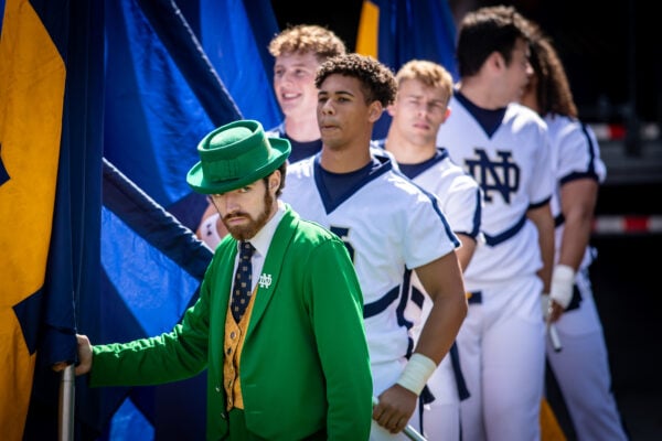 The Notre Dame Leprechaun mascot leads the team onto the field alongside players holding flags before the game on Sept. 26, 2026, at Ross-Ade Stadium, in West Lafayette, Ind. (Photo/Josh Herd)