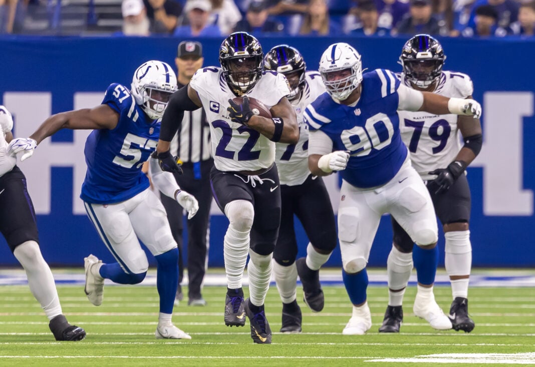 Baltimore Ravens running back Derrick Henry (#22) bursts through the line as Indianapolis Colts defenders, including Jaylon Carlies (#57) and Grover Stewart (#90), pursue him on Sept. 13, 2026, at Lucas Oil Stadium, in downtown Indianapolis, Indiana. (Photo/Walt Thomas)